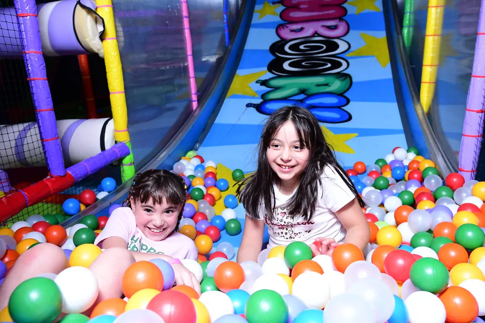 Niñas riendo dentro de la alberca de pelotas