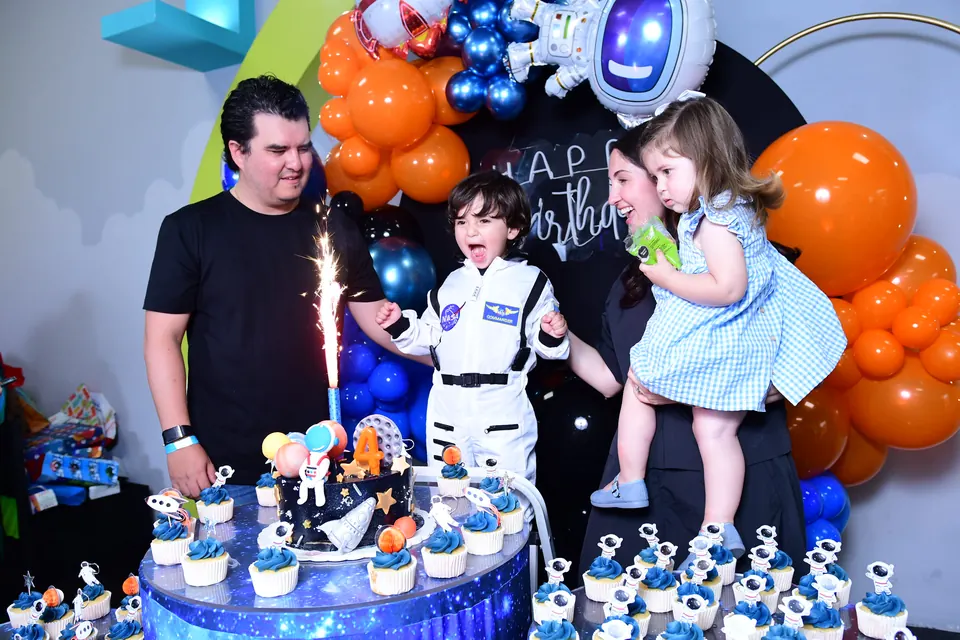 Familia frente al pastel con vela de chispas encendida