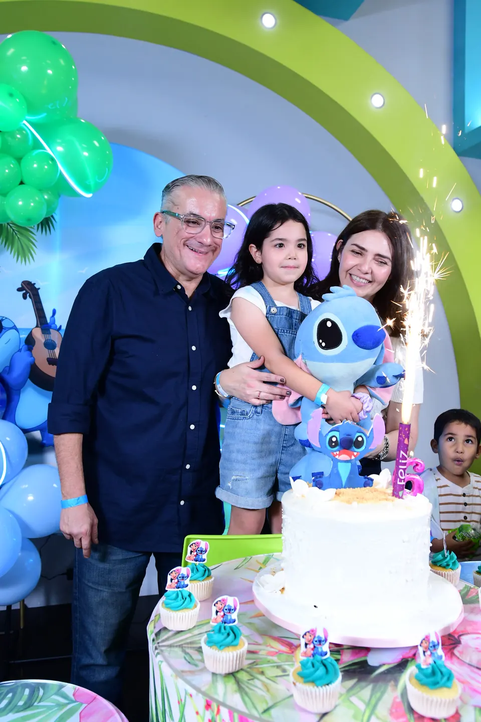 Familia posando junto al pastel con vela de chispas
