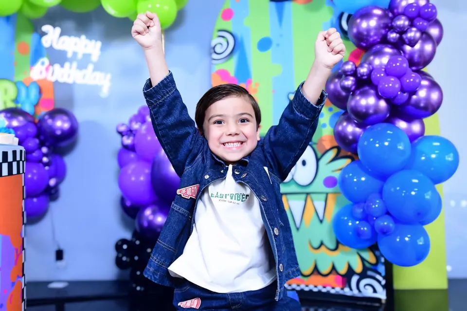 Niño celebrando con los brazos en alto frente a los globos