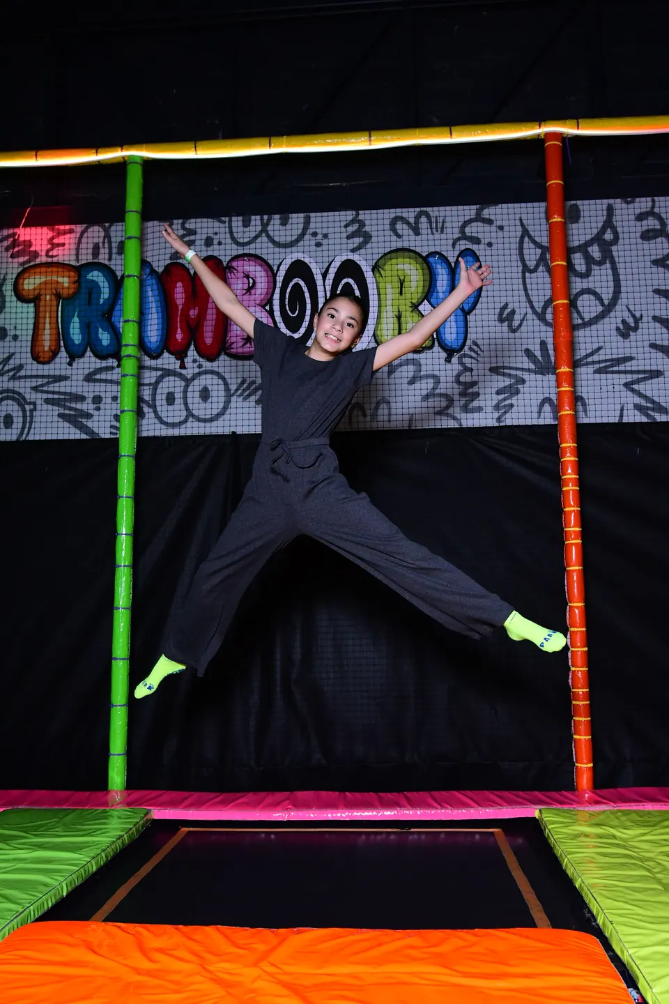 Niño saltando en el trampolín con brazos y piernas abiertos