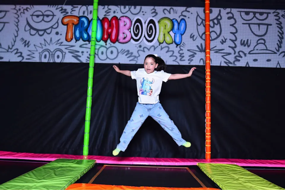 Niña saltando en el trampolín en pose de estrella
