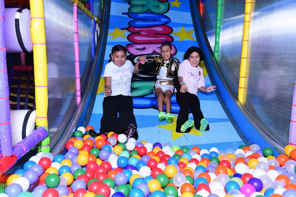 Niños bajando el tobogán hacia la alberca de pelotas